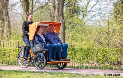 Ein Paar mit zwei E-Bikes vor der Tourist Information. Beide lächeln sich zu. - Foto von © van Raam