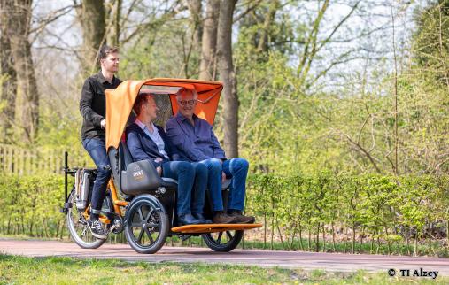 Ein Paar mit zwei E-Bikes vor der Tourist Information. Beide lächeln sich zu. - Foto von © TI Alzey